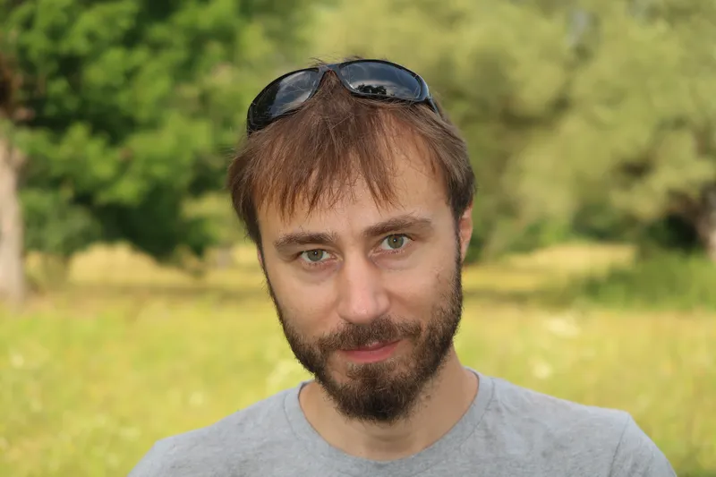 autor románu, v pozadí louka a stromy