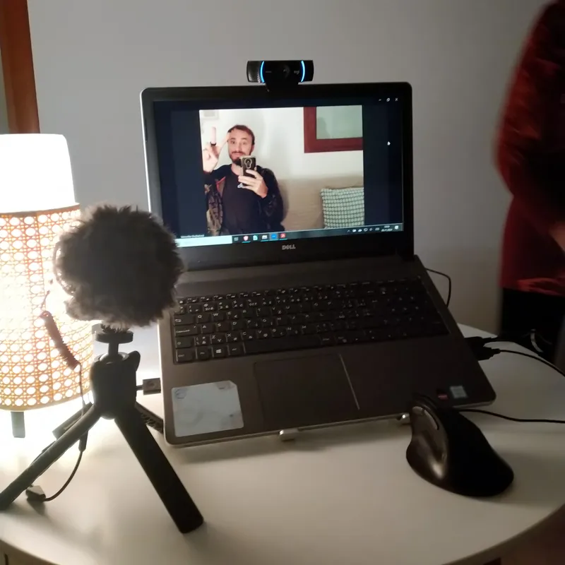 A shot of a laptop with an external camera and microphone connected. The blog author waves from the laptop screen.