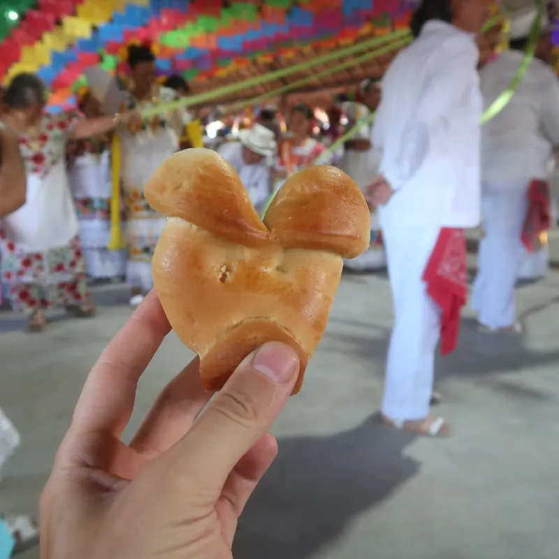 Pečivo ve tvaru prasečí hlavy, na mexické slavnosti, v pozadí papel picado a tanečníci v bílém