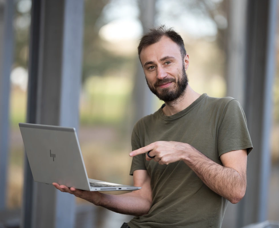 Webový vývojář ukazuje prstem na notebook, který drží v ruce
